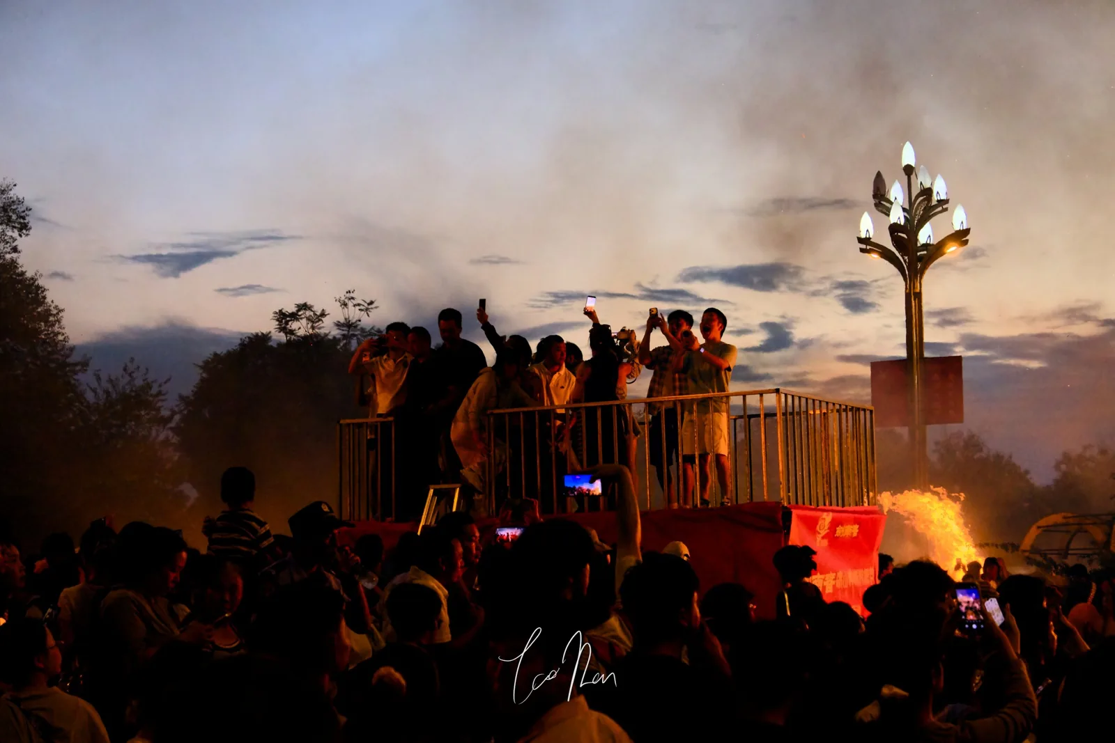 An evening gathering beneath sunset and streetlights
