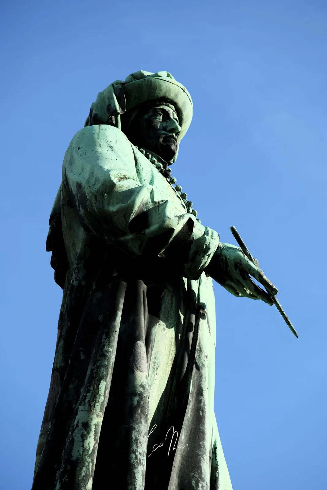 A green bronze statue beneath a blue sky